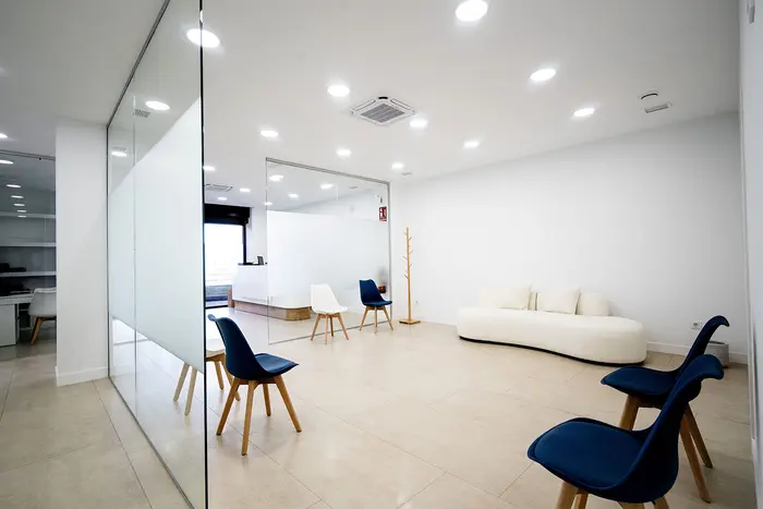 Sala de espera con sofá blanco y sillas azules